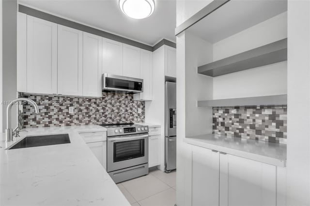 kitchen with white cabinetry, open shelves, a sink, stainless steel appliances, and backsplash