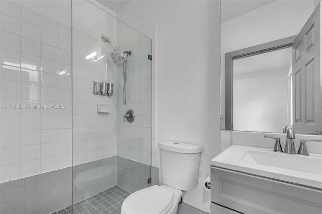 full bathroom with toilet, tiled shower, and vanity