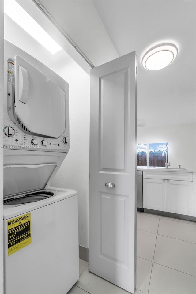 clothes washing area with a sink, stacked washer and dryer, laundry area, and light tile patterned flooring
