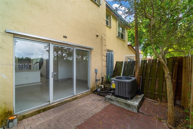 back of property with central air condition unit, a patio, stucco siding, and fence