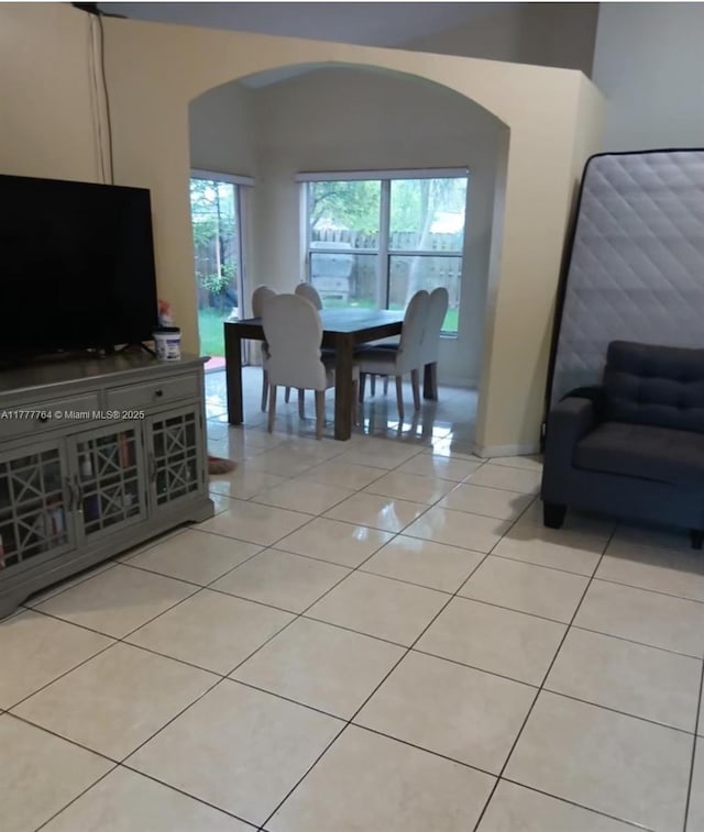 dining area featuring arched walkways and light tile patterned floors