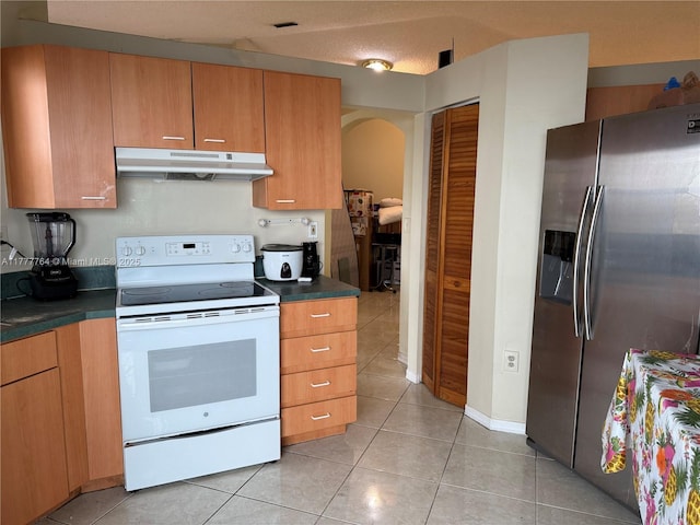 kitchen featuring under cabinet range hood, white range with electric stovetop, stainless steel fridge with ice dispenser, dark countertops, and light tile patterned flooring