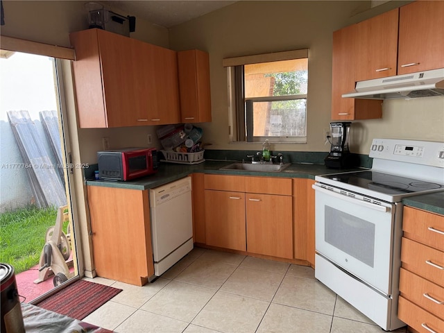 kitchen featuring under cabinet range hood, a sink, white appliances, and light tile patterned floors