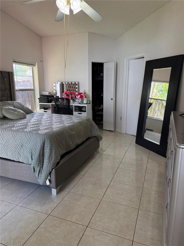 bedroom with vaulted ceiling, a textured ceiling, a ceiling fan, and multiple windows