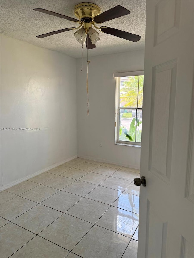 empty room featuring a textured ceiling, a ceiling fan, and light tile patterned floors