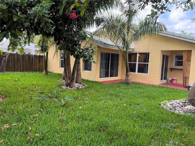 back of property featuring stucco siding, a yard, and fence