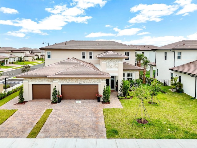 view of front facade featuring a front yard, a garage, stucco siding, a residential view, and decorative driveway