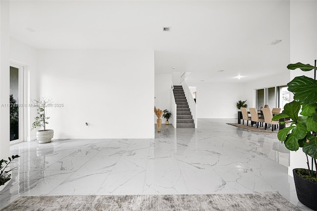 living room with stairway, visible vents, and marble finish floor