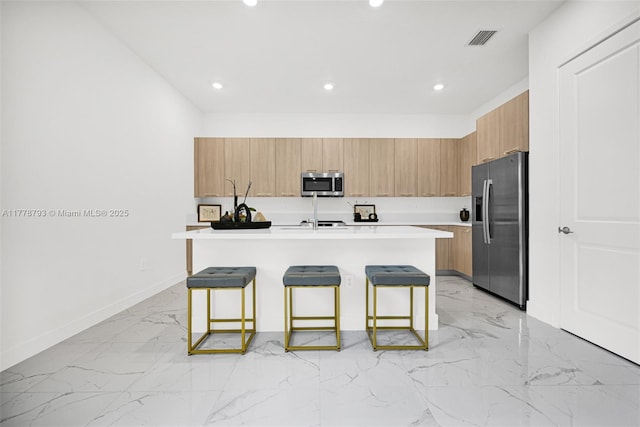 kitchen featuring appliances with stainless steel finishes, marble finish floor, visible vents, and a breakfast bar
