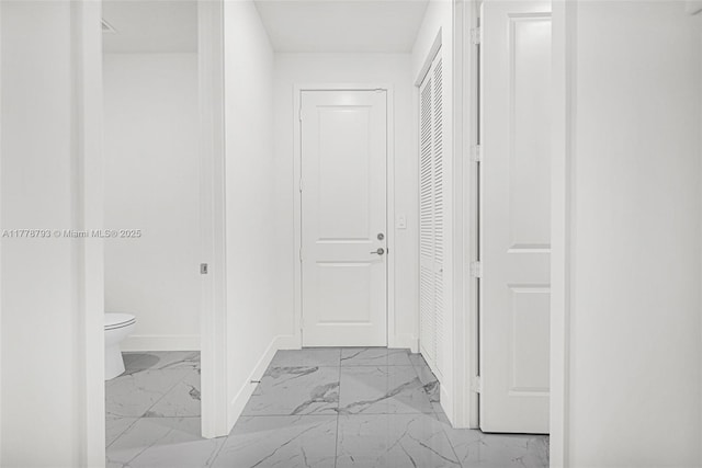 corridor with baseboards and marble finish floor