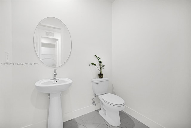 half bath featuring marble finish floor, baseboards, and toilet