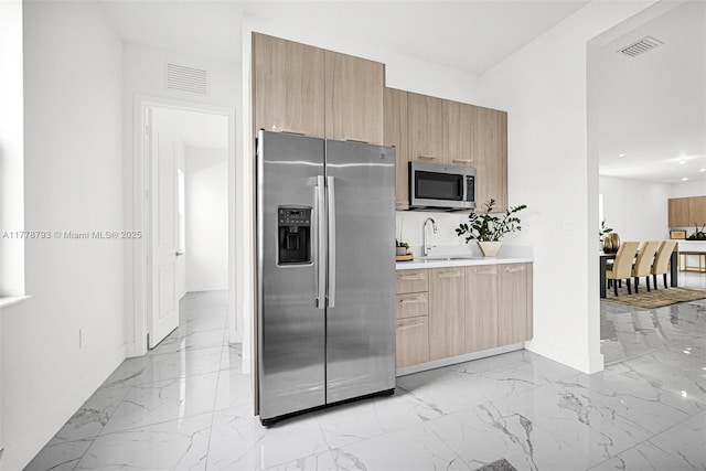 kitchen with appliances with stainless steel finishes, marble finish floor, baseboards, and visible vents