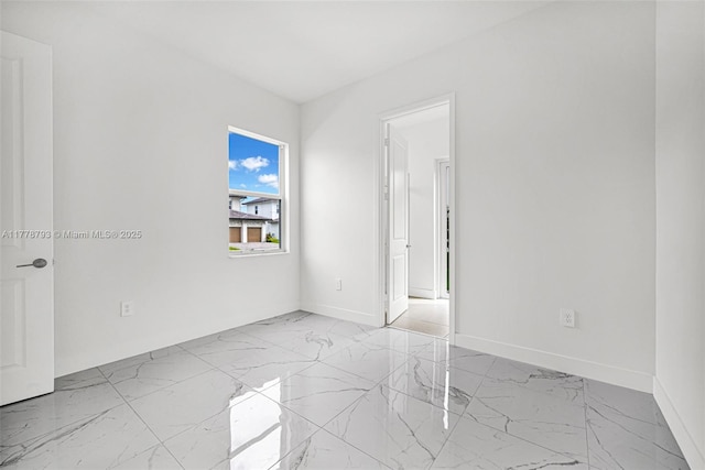 unfurnished room featuring marble finish floor and baseboards