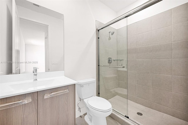 bathroom with a shower stall, tile patterned flooring, vanity, and toilet