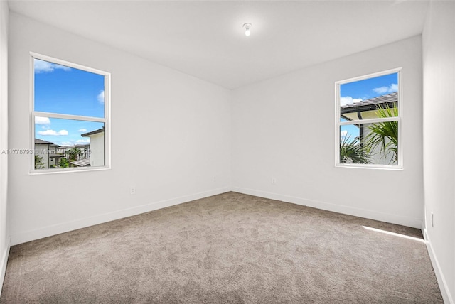 spare room featuring carpet flooring and baseboards