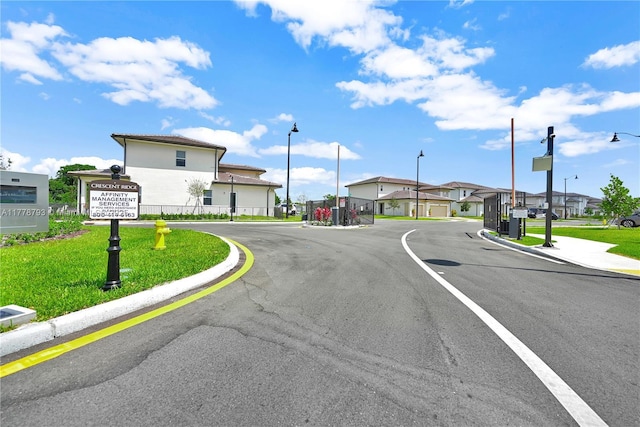 view of road with street lights, curbs, a gated entry, and a residential view