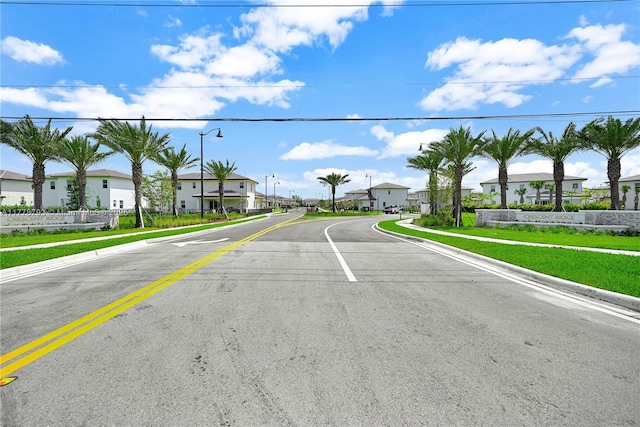 view of street featuring street lights, sidewalks, a residential view, and curbs