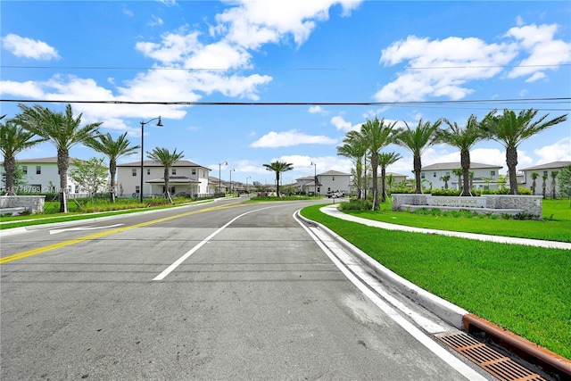 view of street featuring street lighting, sidewalks, curbs, and a residential view