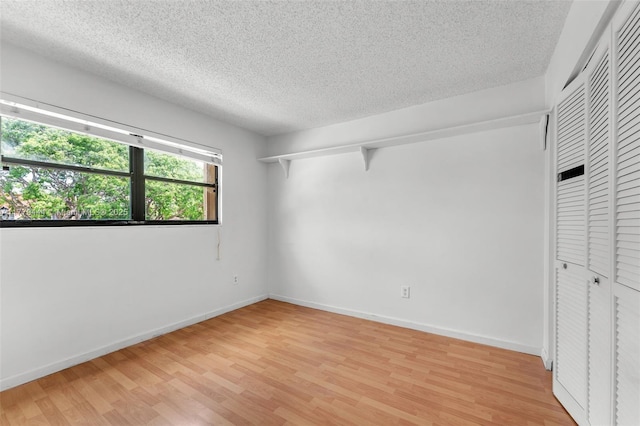 15026 SW 96th Ter, Miami, FL 33196 - unfurnished bedroom featuring a textured ceiling, a closet, light wood finished floors, and baseboards