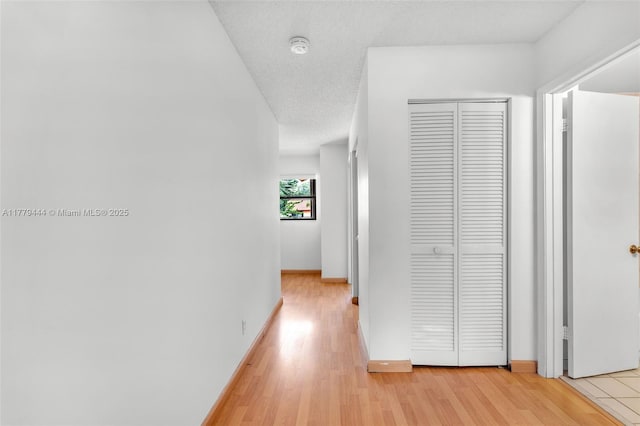 15026 SW 96th Ter, Miami, FL 33196 - hall with light wood-style floors, a textured ceiling, and baseboards