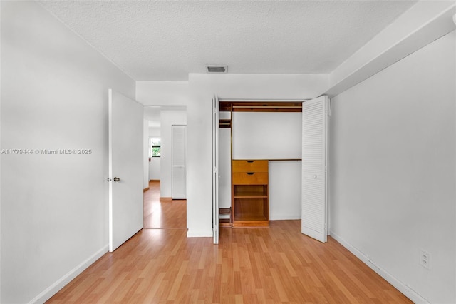 15026 SW 96th Ter, Miami, FL 33196 - unfurnished bedroom with light wood-style flooring, a textured ceiling, a closet, visible vents, and baseboards