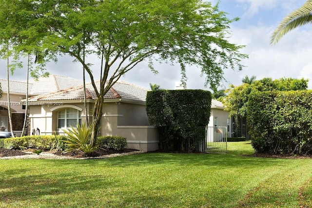 5025 Regency Isles Way, Cooper City, FL 33330 - view of property exterior featuring stucco siding, a gate, a tiled roof, and a lawn