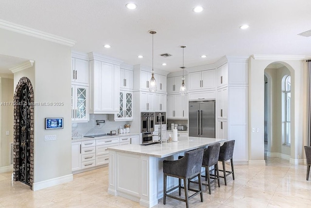 5025 Regency Isles Way, Cooper City, FL 33330 - kitchen featuring stainless steel appliances, a kitchen breakfast bar, arched walkways, white cabinetry, and an island with sink