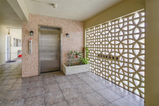 property entrance with a balcony, elevator, and brick siding