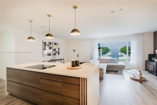 10300 NW 80th Ct, Tamarac, FL 33321 - kitchen with light wood-type flooring, a kitchen island with sink, light countertops, and decorative light fixtures