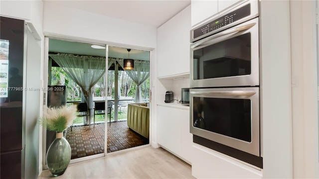10300 NW 80th Ct, Tamarac, FL 33321 - kitchen featuring double oven, white cabinetry, modern cabinets, wood finished floors, and light countertops