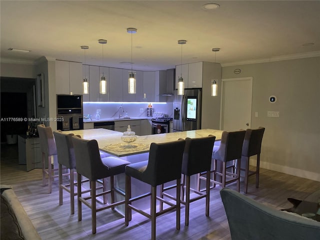 428 N Crescent Dr, Hollywood, FL 33021 - kitchen featuring appliances with stainless steel finishes, a sink, wood finished floors, white cabinets, and a breakfast bar