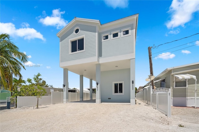rear view of house featuring stucco siding, fence, and a carport