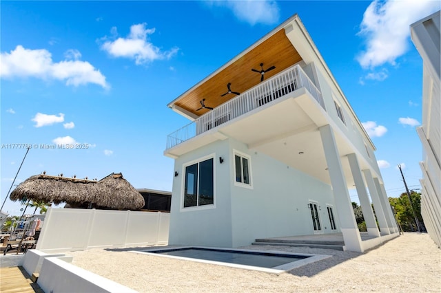 rear view of house with stucco siding, fence, and a balcony
