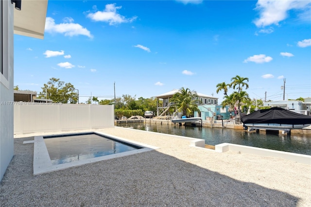 pool with boat lift, a boat dock, a water view, and fence
