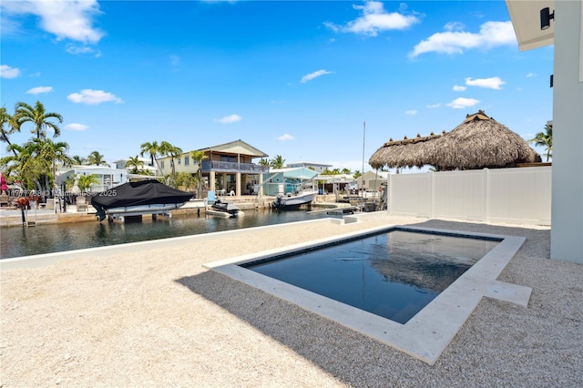 pool featuring a boat dock, a water view, and fence