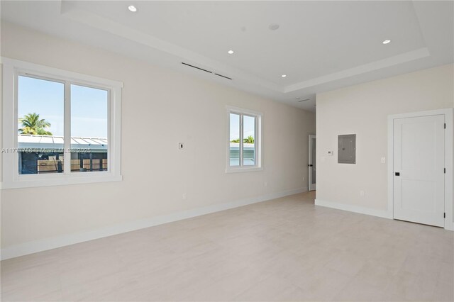 spare room with baseboards, recessed lighting, electric panel, and a raised ceiling