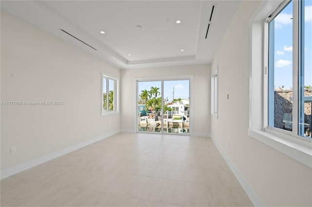 empty room featuring a tray ceiling, baseboards, and recessed lighting