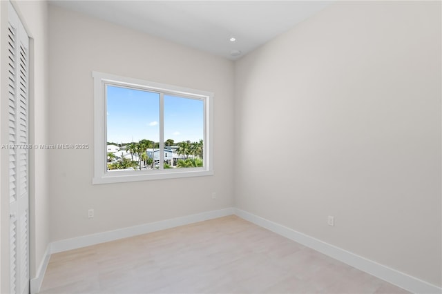 spare room featuring light floors and baseboards