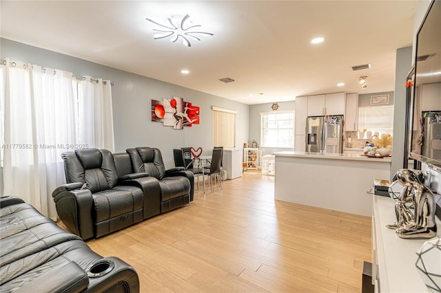 living area with light wood-type flooring, visible vents, and recessed lighting