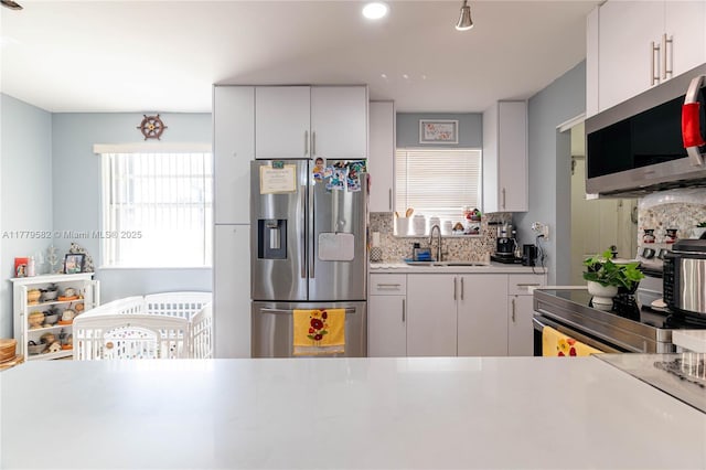 kitchen with a sink, light countertops, recessed lighting, stainless steel appliances, and decorative backsplash