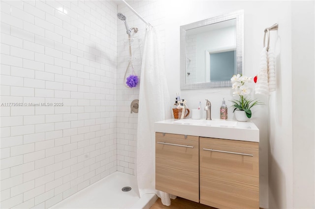 full bathroom featuring a tile shower and vanity