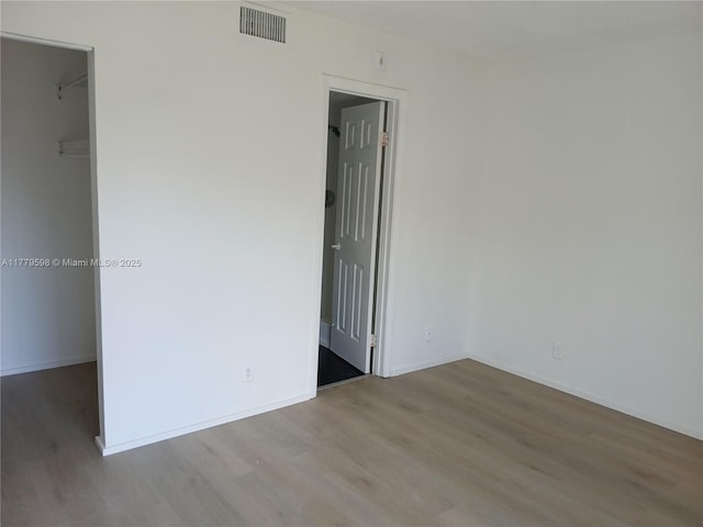 spare room with visible vents, baseboards, and wood finished floors