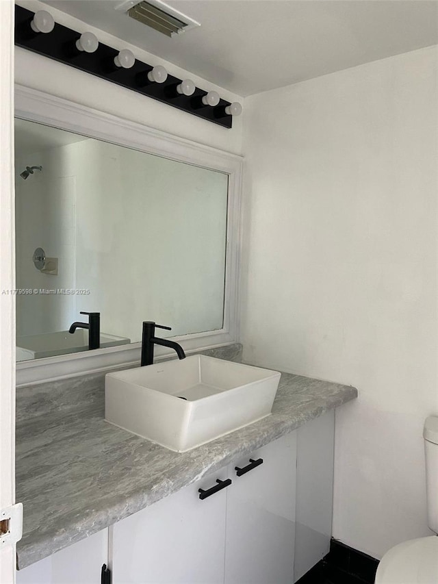 bathroom featuring visible vents, toilet, and vanity
