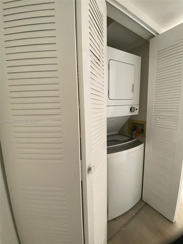 clothes washing area featuring stacked washer / dryer and laundry area