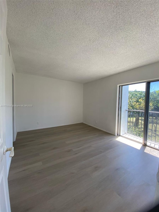 unfurnished room featuring a textured ceiling, baseboards, and dark wood-style flooring