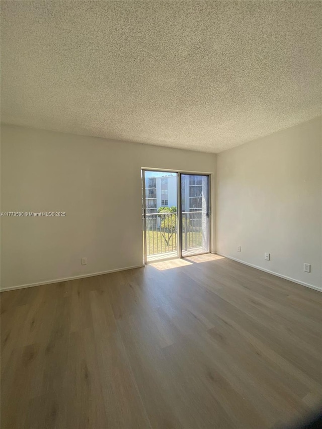 unfurnished room featuring wood finished floors, a textured ceiling, and baseboards