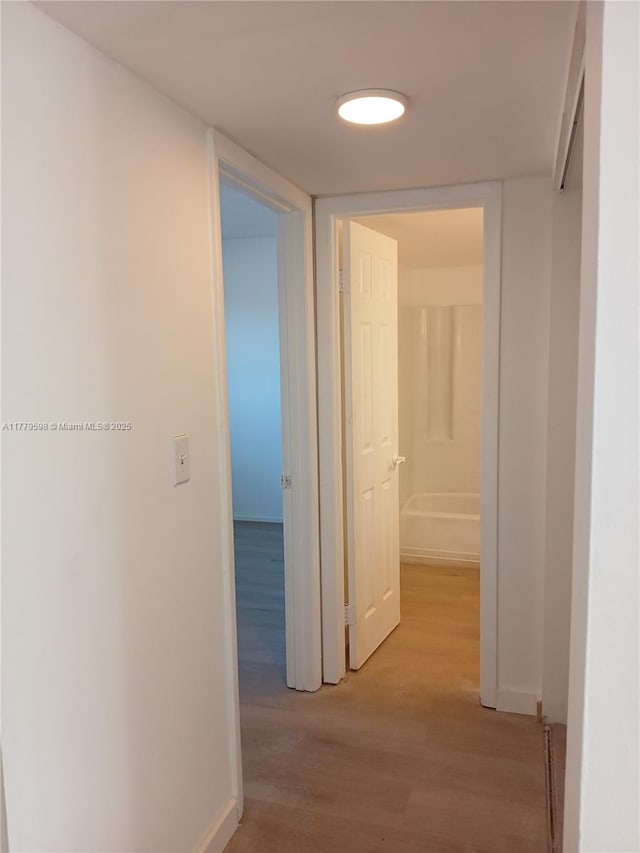 hallway with light wood-style flooring and baseboards