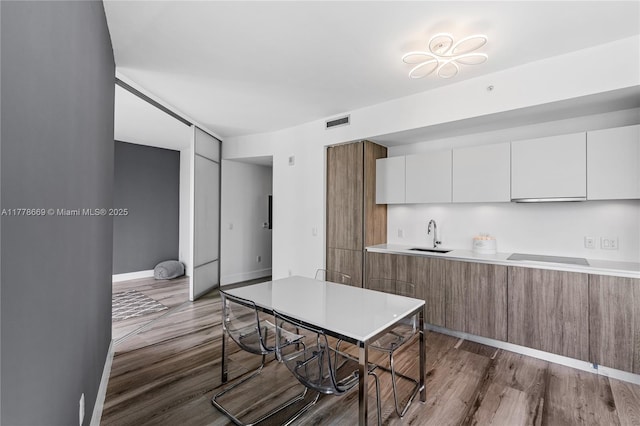 2900 NE 7th Ave Unit 1609, Miami, FL 33137 - kitchen featuring wood finished floors, light countertops, modern cabinets, white cabinets, and brown cabinetry