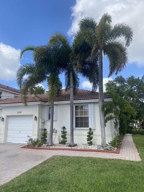 18769 SW 28th St, Miramar, FL 33029 - ranch-style home with stucco siding, a garage, decorative driveway, and a front yard