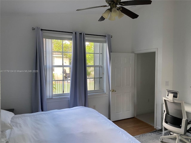 bedroom with a ceiling fan, wood finished floors, and multiple windows